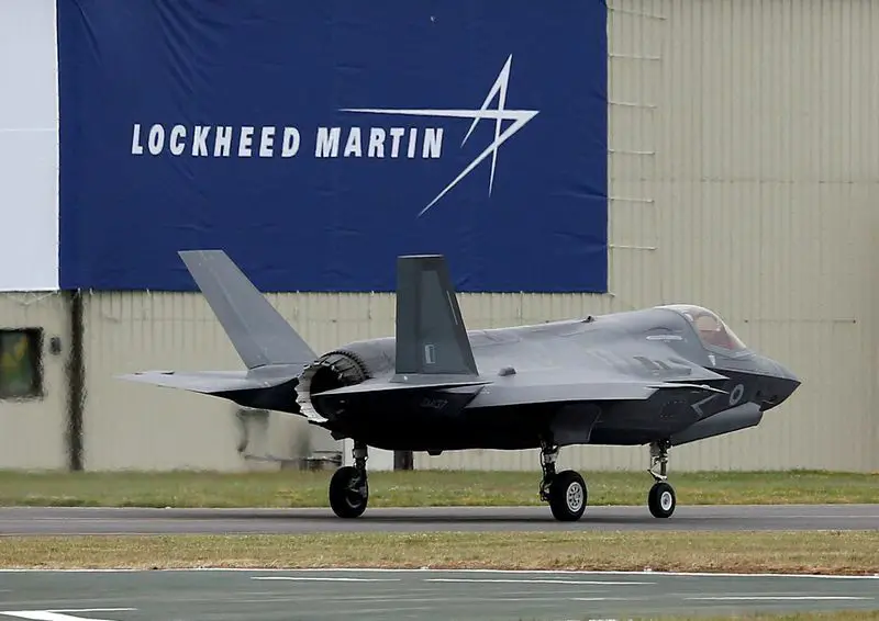 Avión caza de combate con bandera de Lockheed Martin detrás