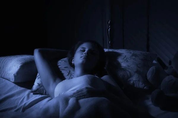 Mujer durmiendo en habitación sin luz.