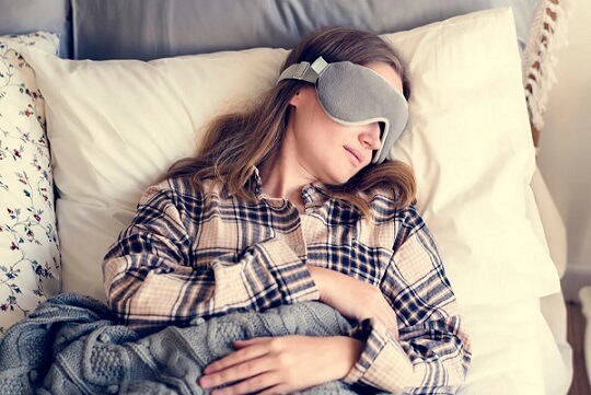 Mujer acostada boca arriba durmiendo con antifaz