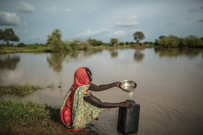 Mujer recogiendo agua de laguna