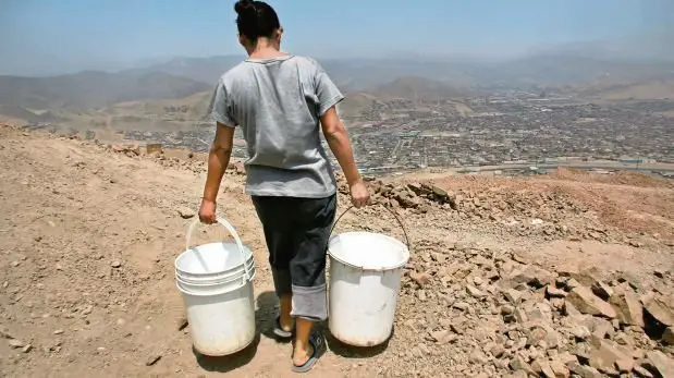 hombre llevando cubetas de agua en un cerro