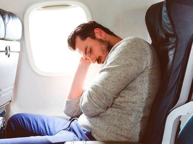 Hombre durmiendo sentado en asiento de avión