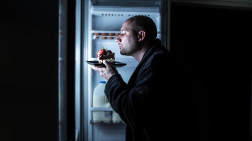 Hombre comiendo de noche en el refrigerador